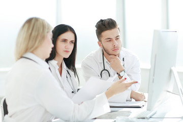 medical professionals are discussing something sitting at the office Desk
