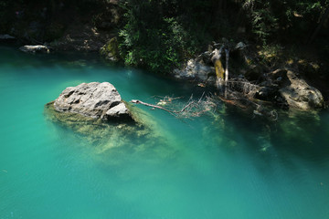A large stone in calm turquoise water inside the cave as the background.