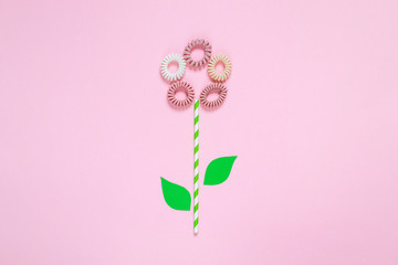 Flowers from hair spiral scrunchies on pink background, creative spring concept, flat lay, woman's day