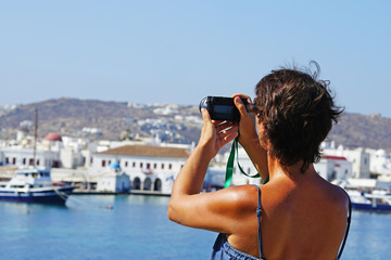 Fototapeta na wymiar A tourist takes photos of Chora in Mykonos, Cyclades
