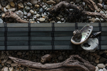 Dark composition of few marine items on wooden bar over sea pebbles.