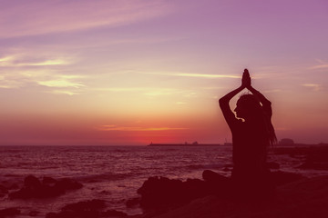 Silhouette yoga woman on the beach at sunset. Meditation.