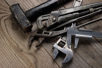 Old tools lie on a wooden table. Hammer and adjustable wrenches.