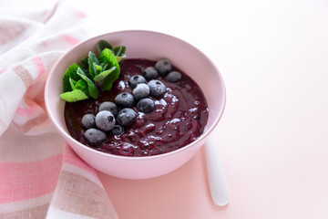 healthy berry smoothie bowl with banana on pink background. Vegetarian food or detox concept. Selective focus