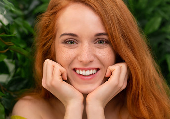 Nice shiny red-haired girl holding chin with fists