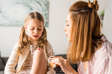 Worried mother treating injured kid with antiseptic