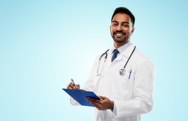 medicine, profession and healthcare concept - smiling indian male doctor in white coat with stethoscope and clipboard over blue background