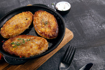 Close up view on burger, cutlets in pan, which stands on cutting board. Fried cutlets with sauсe and herbs. food menu, recipe concept. Copy space