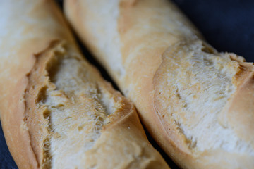 Macro view of freshly baked crunchy baguette bread on dark background. Closeup of crust of bread...