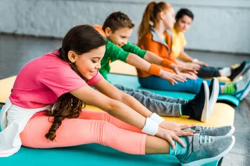 Gordijnen Group of kids stretching in gym together © LIGHTFIELD STUDIOS