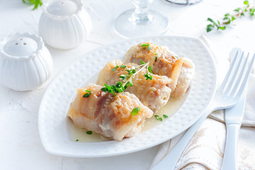 Chicken rolls with bacon and cheese on a white table, horizontal