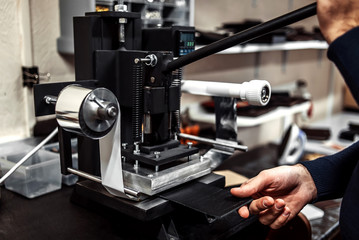 the master makes an impress on a piece of leather on the machine
