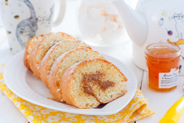 Biscuit roll with boiled condensed milk on a white plate, selective focus