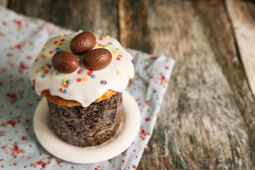 Traditional Easter cake kulich decorated with icing and chocolate eggs