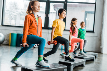 Preteen kids training with dumbbells and step platforms
