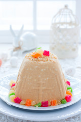 Traditional curd Easter with condensed milk, nuts and candied fruits on a white plate in a festive light decor, selective focus