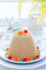 Traditional curd Easter with condensed milk, nuts and candied fruits on a white plate in a festive light decor, selective focus