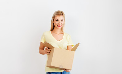people and moving to new place concept - happy woman holding cardboard box