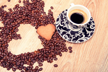 Heart make whit coffee beans and cup whit espresso and sweet heart cookie on wood table background. 