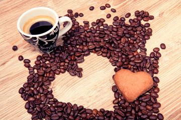 Heart make whit coffee beans and cup whit espresso and sweet heart cookie on wood table background. 