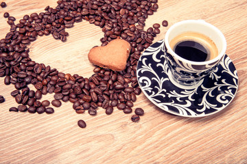 Heart make whit coffee beans and cup whit espresso and sweet heart cookie on wood table background. 