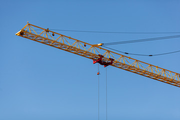 The yellow crane in the daylight. Construction technology. Modern construction crane for lifting building materials