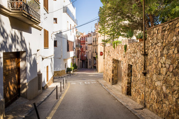 Streets and buildings in the city of Tossa de Mar, Spain. Narrow passages between houses. Shops and restaurants in the center.