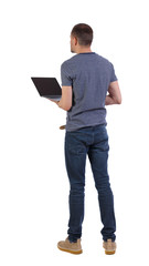 Back view of a man who is standing with a laptop.