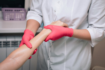 Beautician removes hair from a woman's hand. Sugaring. Hair removal with a special sugar paste has many advantages over wax depilation.  Close-up.
