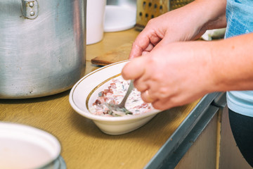 Stir the mayonnaise in a plate on the background of the pan