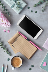 Springtime flat lay with pearl hyacinth flowers, eucalyptus, mobile phone, notebook and gift postcards on stone