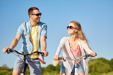Obraz premium people, leisure and lifestyle concept - happy young couple riding bicycles in summer