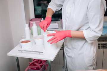 sugaring master in pink gloves holds Wand with sugaring wax. depilation and beauty concept.