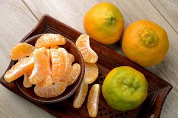 tangerines or orange fruit slices in a bowl on wooden table