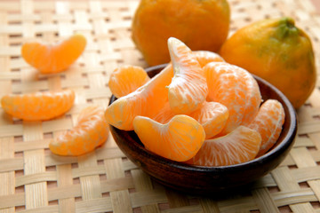 tangerines or orange fruit slices in a bowl on wooden table