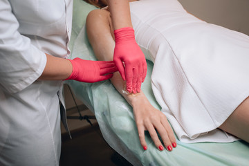 Obraz premium Beautician removes hair from a woman's hand. Sugaring. Hair removal with a special sugar paste has many advantages over wax depilation. Close up.