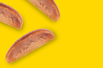 Chaotically scattered rectangular wholes black breads with grain on table with yellow countertop on cuisine. Copy space for your text. Top view. Cooking concept