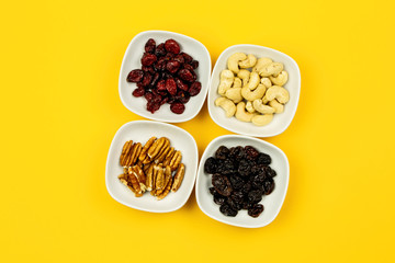 Vegan breakfast: variety of fruits, nuts and berries on yellow background