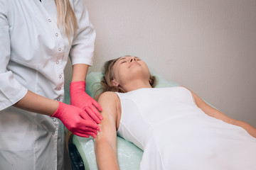 Beautician removes hair from a woman's hand. Sugaring. Hair removal with a special sugar paste has many advantages over wax depilation. Close-up.