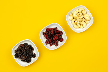 Vegan breakfast: variety of fruits, nuts and berries on yellow background