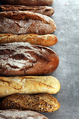 Assortment of baked bread and bread rolls on stone table background