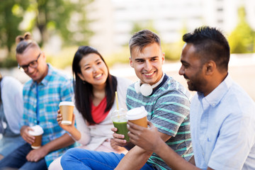 people, friendship and international concept - group of happy friends drinking coffee and juice talking in city