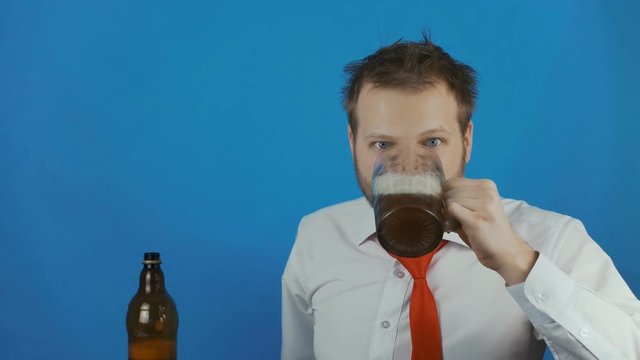 unshaven careless businessman like a alcoholic pours beer into a mug and drinks ale or lagger