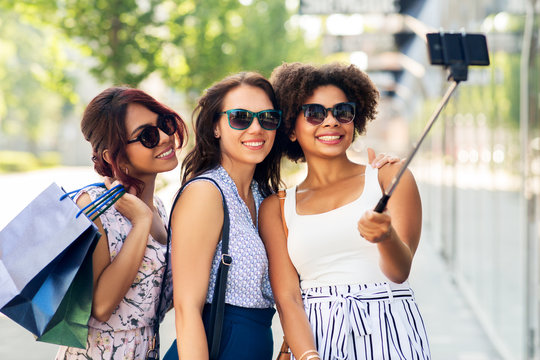 sale, friendship and technology concept - happy young women with shopping bags taking selfie by smartphone in outdoors
