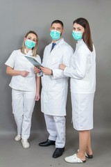 Fototapeta premium Male doctor and two female nurses on grey background, isolated, concept