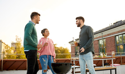 leisure and people concept - happy friends with bbq grill and non alcoholic drinks having barbecue party on rooftop