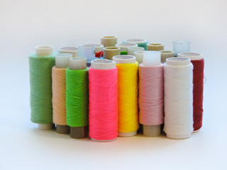 Colorful treads for sewing.Sewing supplies and accessories for needlework- scissors, needles, yellow measuring tape, thread on a table. Close up group of Multicolored spools of thread use to sewing. 