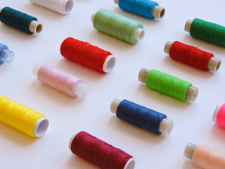 Colorful treads for sewing.Sewing supplies and accessories for needlework- scissors, needles, yellow measuring tape, thread on a table. Close up group of Multicolored spools of thread use to sewing. 