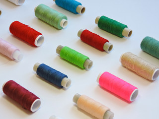 Colorful treads for sewing.Sewing supplies and accessories for needlework- scissors, needles, yellow measuring tape, thread on a table. Close up group of Multicolored spools of thread use to sewing. 