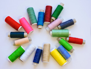 Colorful treads for sewing.Sewing supplies and accessories for needlework- scissors, needles, yellow measuring tape, thread on a table. Close up group of Multicolored spools of thread use to sewing. 